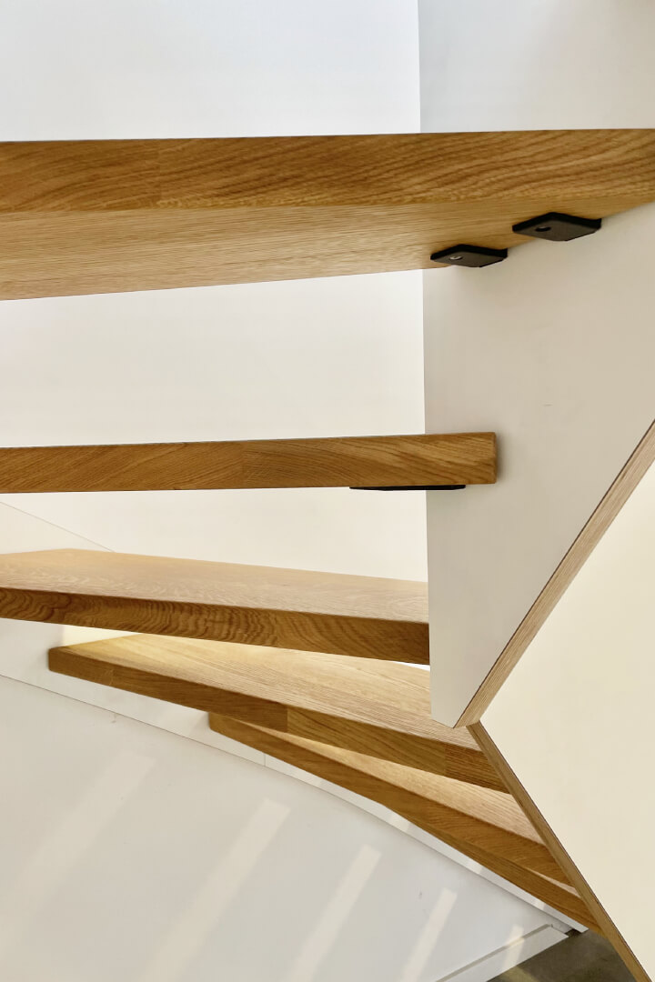 Blick von unten auf die Designwangentreppe mit offener Multiplexkante und den Trittstufen in Eiche gebürstet